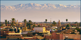 Enquête sur le comportement de paiement des entreprises au Maroc : des délais raccourcis en 2021. Image de l'horizon de la ville de Marrakech au Maroc avec les montagnes enneigées de l'Atlas en arrière-plan.
